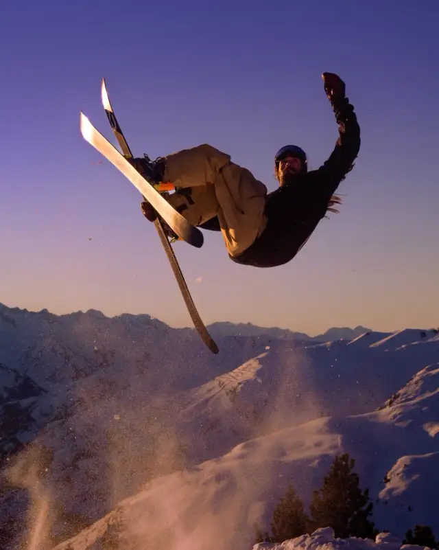 Freestyle skier spinning off a jump at sunset