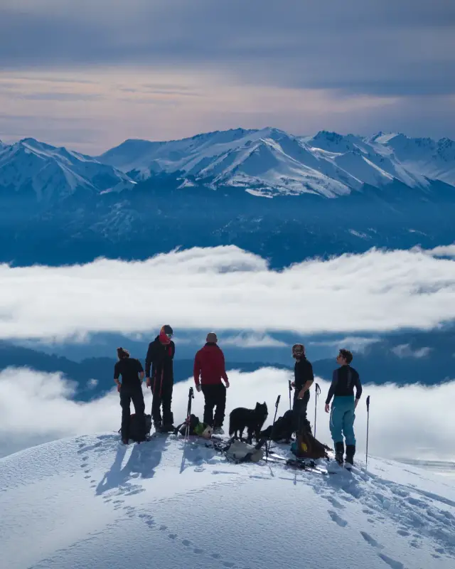 Group of ski tourers on a summit above the clouds